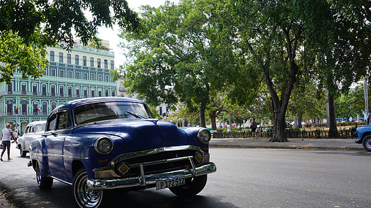 blue car parked beside a sidewalk thumbnail