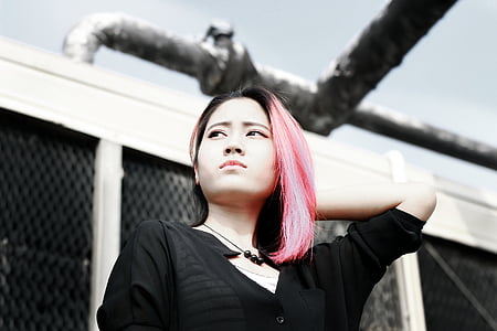 pink-haired woman wearing black shirt standing near white building thumbnail