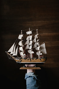 person holding brown wooden galleon ship thumbnail