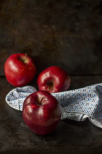 three red apples beside blue and white textile thumbnail