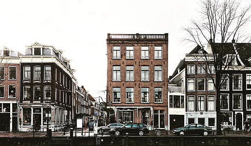 cars passing by brown buildings thumbnail