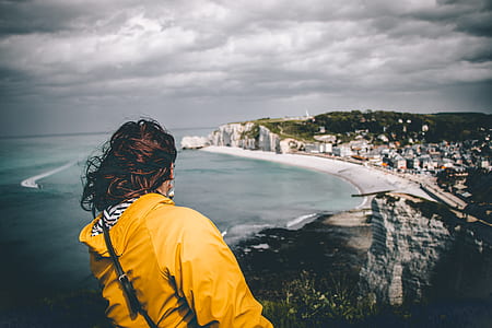 woman standing on mountain far from ocean and building under white clouds thumbnail
