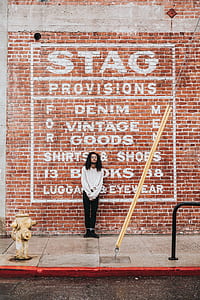 man standing near brown wall bricks thumbnail