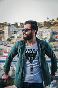 Man in Green Long-sleeved Top Leaning of Silver Railings Outdoors thumbnail
