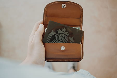 person holding brown leather wallet with Starbucks card thumbnail