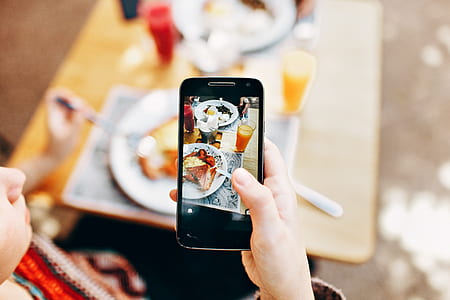 Person Holding Phone Taking Picture of Served Food thumbnail