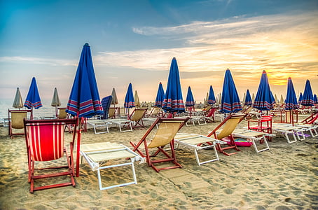 assorted-color chair with umbrella on beach near the water during golden hour thumbnail