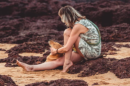 Woman With Green Floral Sleeveless Mini Dress Sitting on Brown Sand Close-up Photography thumbnail