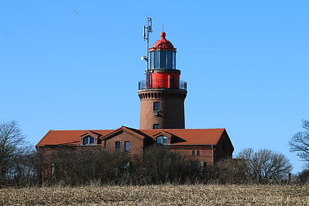 brown and red lighthouse under blue sky at daytime thumbnail