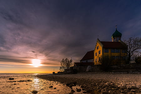 house on seashore under cloudy sky thumbnail