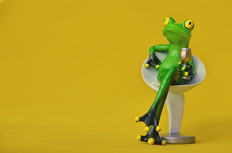 green frog sitting on white stall chair holding wine glass thumbnail