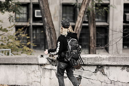 man holding skateboard standing near building thumbnail