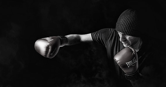 grayscale photo of man wearing beanie and Everlast boxing gloves thumbnail