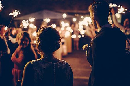 grayscale photography of man and woman in front of group of people holding fireworks thumbnail