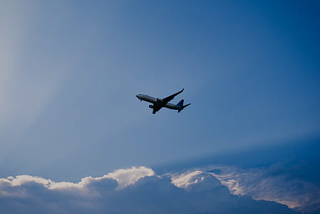 low angle photo of gray and white plane flying under blue sky thumbnail