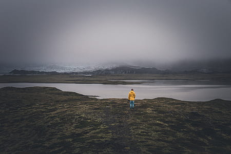 person wearing yellow shirt standing near lake thumbnail