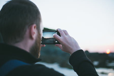 person holding a smartphone taking a photo of golden hour thumbnail