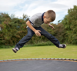 boy playing on trampoline during daytime thumbnail
