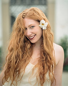 smiling woman with white flower on her ear thumbnail