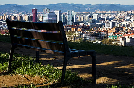 Brown Wooden Bench With Metal Frame Surrounded by Building Scenery thumbnail