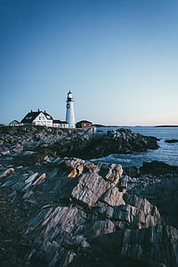 lighthouse beside ocean under clear blue sky during daytime thumbnail