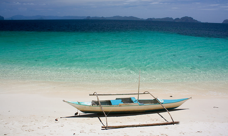 teal and white boat on seashore