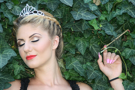 woman wearing tiara lying on green leaves photography thumbnail