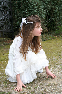 girl in white long-sleeved dress posing near green bushes thumbnail