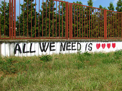 white painted wall with All We Need is heart text-printed vandal during daytime thumbnail