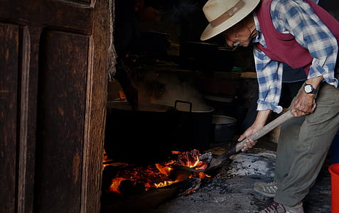 man holding shovel standing near cooking pot thumbnail
