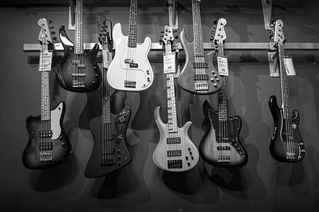 grayscale photography of electric guitars hanging on rack thumbnail