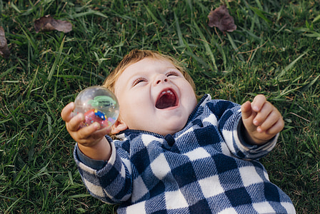 boy lying on green grass holding ball thumbnail