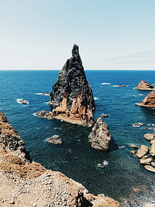 gray and brown rocky cliff surrounded by body of water thumbnail