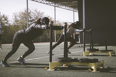 two woman wearing black caps doing exercise during daytime thumbnail