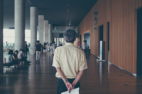man holding white paper while standing facing people near post thumbnail