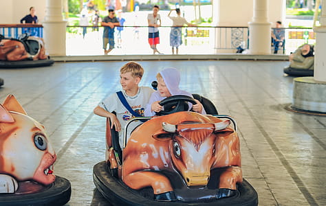 Two Boys Riding on Orange and Black Bumper Car thumbnail