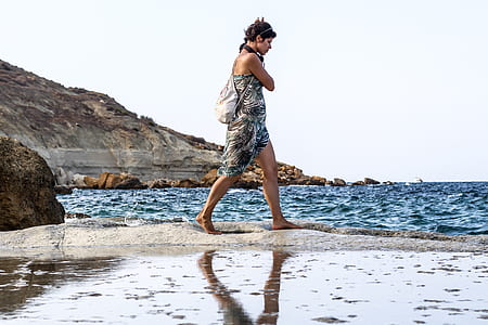 woman walking on gray sand under gray sky thumbnail
