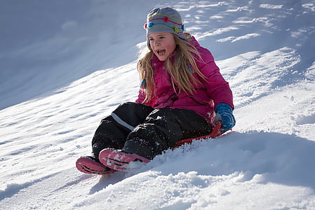 girl riding on sled during daytime thumbnail