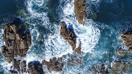 aerial photography of ocean wave crashing on rock formation at daytime thumbnail
