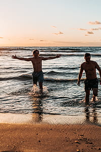 two men walking on sea spreading arms during sunset thumbnail