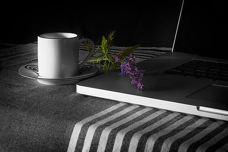 white ceramic mug on saucer beside black laptop thumbnail