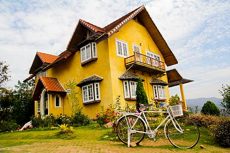 white commuter bike beside yellow house thumbnail