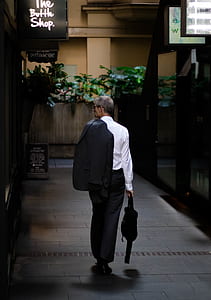 man carrying bag and blazer walking at hallway thumbnail