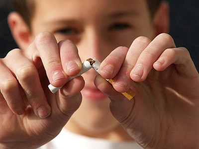 man holding white and brown cigarette stick thumbnail