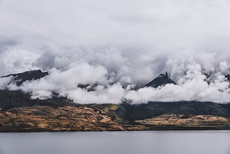 mountain covered with clouds near body of water thumbnail
