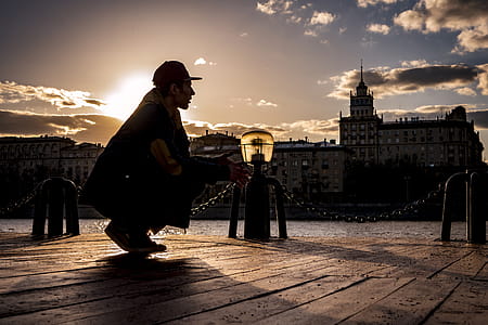 Silhouette of Man Squatting Near Body of Water during Sunset. thumbnail