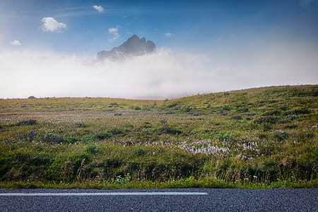 landscape photography of street beside grass field away from mountain thumbnail