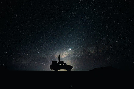 silhouette photo of person standing on vehicle roof viewing starry sky during nighttime thumbnail