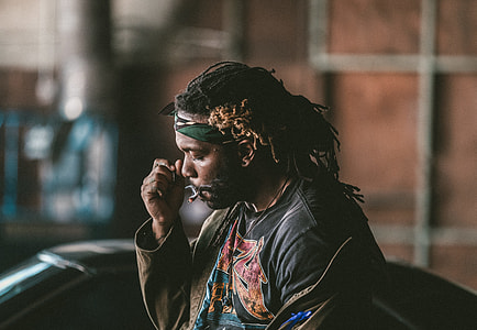selective focus photography of man smoking near black vehicle at daytime thumbnail