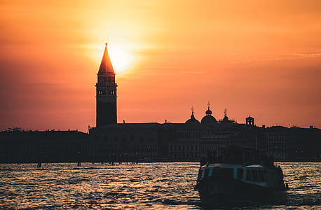 silhouette photo of boat near concrete chapel during golden hour thumbnail